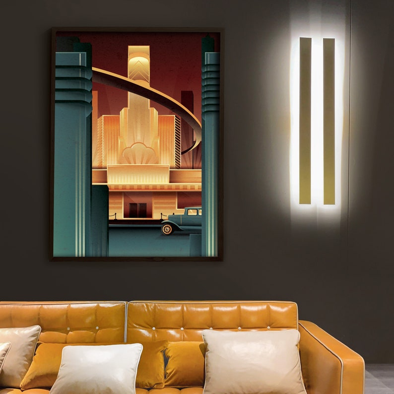 May include: A vintage-style illustration of a city skyline with a car in the foreground. The illustration is in a dark brown frame and is hanging on a gray wall above a brown leather couch.