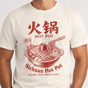 Könnte beinhalten: Ein cremefarbenes T-Shirt mit Rundhalsausschnitt und einer roten Grafik eines Sichuan-Hot-Pots. Das Design enthält chinesische Schriftzeichen sowie den Text "HOT POT", "SICHUAN HOT POT" und "WHERE SPICE MEETS SOUL." Die Grafik zeigt einen Topf.