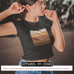 May include: Black crop top featuring the text "HATE IS A VIRUS" in a stacked, retro design. The text is in white, yellow, orange, and brown. A casual, everyday wear item.