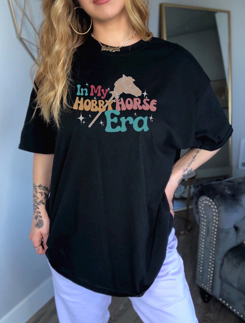May include: Black oversized t-shirt with a graphic of a hobby horse and the text "In My Hobby Horse Era".