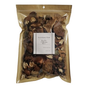 May include: A clear plastic bag filled with dried botanicals, sealed with a brown paper top. The bag contains a mix of brown, beige, and tan plant matter. A white label reads "Spiritual Kids" and "Bay Mix + Cypress".