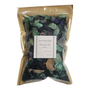 May include: A brown paper bag with a clear plastic window, filled with green, blue, and brown potpourri. The bag has a label that reads "Spiritual Kids Stargazer" with the word "Fragrance" underneath.