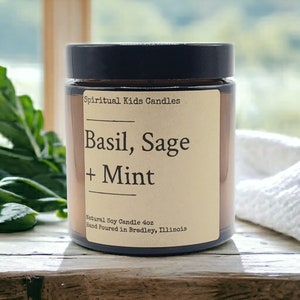 Puede incluir: Una vela de vidrio marrón en un frasco con tapa negra. La etiqueta es beige con texto negro que dice "Spiritual Kids Candles", "Basil, Sage + Mint", "Natural Soy Candle 4oz" y "Hand Poured in Bradley, Illinois".