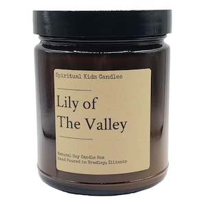 Puede incluir: Un tarro de vela de vidrio marr&oacute;n con una tapa negra. La etiqueta es marr&oacute;n con texto blanco que dice "Spiritual Kids Candles", "Lily of" y "The Valley". La etiqueta tambi&eacute;n incluye el texto "Natural Soy Candle 6oz" y "Hand Poured in Bradley, Illinois".