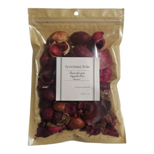 May include: A brown paper bag with a zipper closure contains a mix of potpourri. The potpourri is a mix of dried flowers, leaves, and spices. The bag has a label that says "Spiritual Kids" and "Brand: Grandma's Apple Pie Potpourri".