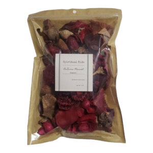 May include: A clear plastic bag filled with potpourri. The potpourri is a mix of dried flowers, leaves, and spices in shades of red, brown, and orange. The bag has a label that reads "Spiritual Kids Autumn Harvest Fragrance".