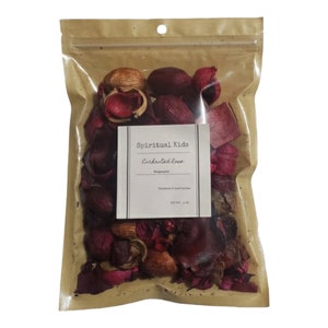 May include: A clear plastic bag filled with dried potpourri. The potpourri includes red, brown, and tan pieces. A white label on the bag reads "Spiritual Kids Enchanted Rose". The bag is sealed with a brown paper top.