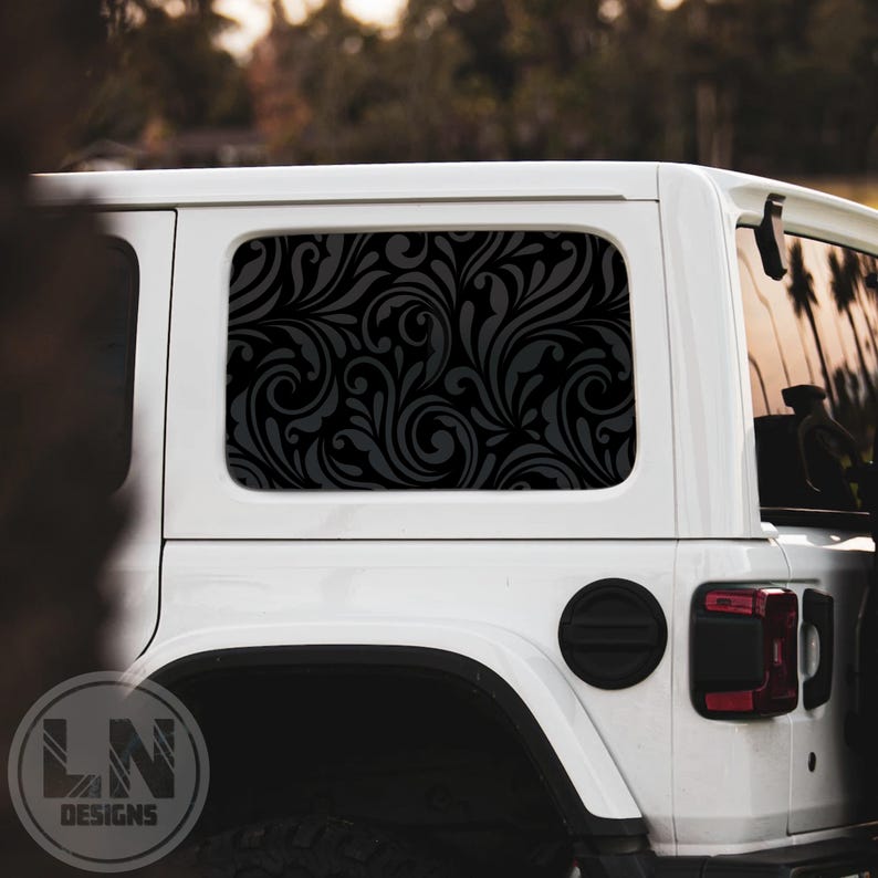 May include: A white Jeep with a black and gray floral pattern window decal. The decal covers the entire rear window.