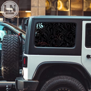 May include: A white Jeep Wrangler with a black swirl pattern decal on the rear window. The decal is a decorative design that covers the entire window.