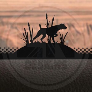 Op de afbeelding: Zwarte silhouet van een jachthond die door hoog gras rent. De hond bevindt zich in een veld met riet en lisdodde.