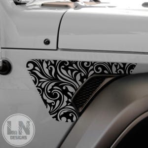 May include: A black and white floral design decal for a Jeep Wrangler. The decal is applied to the fender of the vehicle and features a swirling pattern.