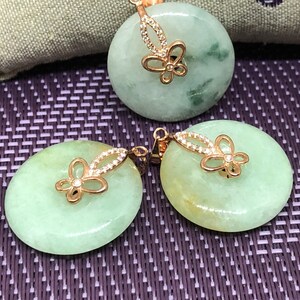 May include: A set of two jade pendants with butterfly designs. The pendants are green and have a gold-tone finish. The butterflies are adorned with small, clear stones.