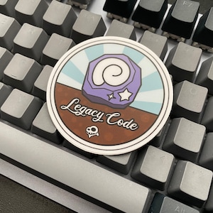 May include: A round sticker with a brown background and a blue and white striped design. The sticker features a purple fossil with a white star and the text "Legacy Code".