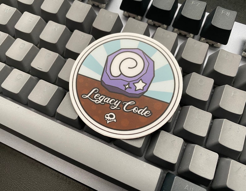 May include: A round sticker with a brown background and a blue and white striped design. The sticker features a purple fossil with a white star and the text "Legacy Code".