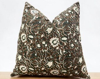 May include: A brown and green throw pillow with a white floral pattern. The pillow is made of a soft, comfortable fabric and is perfect for adding a touch of style to any room.