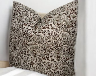 May include: A brown and cream patterned throw pillow with a paisley design.
