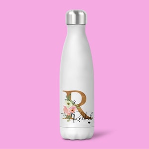 Puede incluir: Botella de agua de acero inoxidable blanca con un diseño floral y la letra "R" en dorado. El nombre "Rachel" está escrito en letra negra debajo de la letra.