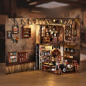 May include: A detailed wooden model of a vintage garage, featuring multiple levels with tools, shelves, and a classic car. The model includes miniature posters, a staircase, and lighting, creating a realistic scene.