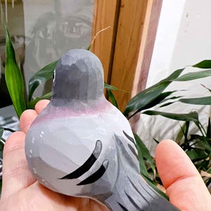 以下が含まれることがあります： 灰色と黒で塗られた手彫りの木製の鳥の置物。鳥は丸い体と長い尾を持っています。鳥は写実的なデザインで描かれています。