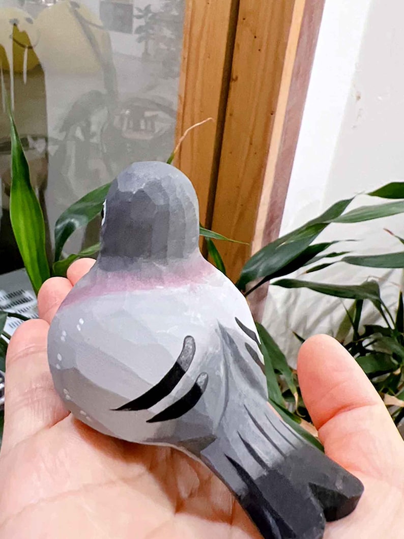 以下が含まれることがあります： 灰色と黒で塗られた手彫りの木製の鳥の置物。鳥は丸い体と長い尾を持っています。鳥は写実的なデザインで描かれています。