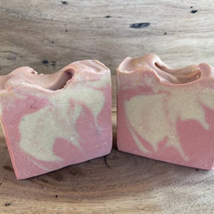May include: Two bars of handmade soap with a pink and white swirl pattern. The soap is made with natural ingredients and is perfect for sensitive skin.