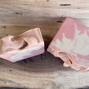 May include: Two bars of handmade soap with a swirl pattern in shades of pink and white.