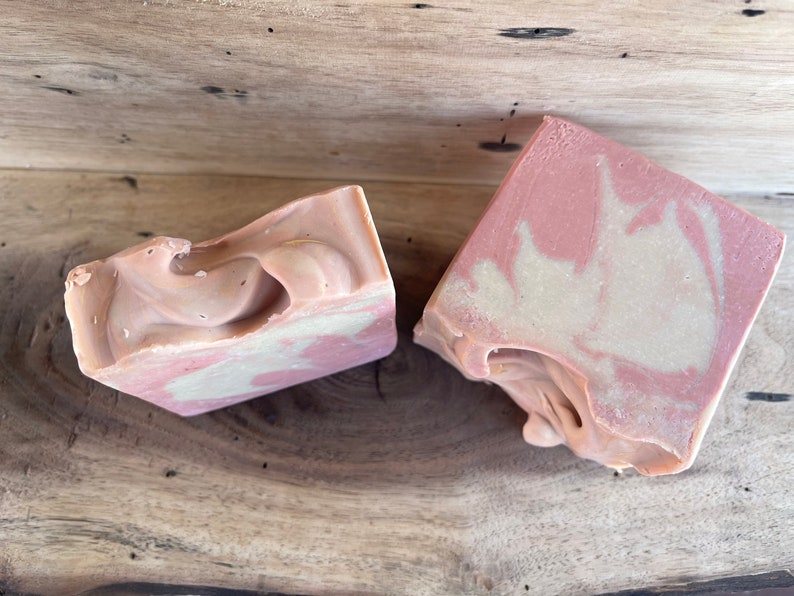 May include: Two bars of handmade soap with a swirl pattern in shades of pink and white.