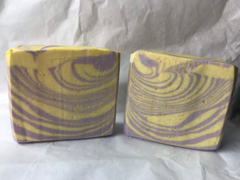May include: Two bars of handmade soap with a swirl pattern in shades of yellow and purple.