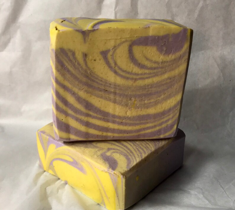 May include: Two bars of handmade soap with a swirl pattern in shades of yellow and purple.