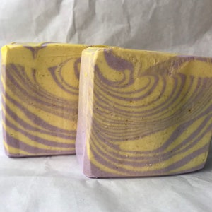 May include: Two bars of handmade soap with a swirl pattern in shades of yellow and purple.