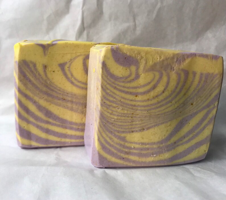 May include: Two bars of handmade soap with a swirl pattern in shades of yellow and purple.