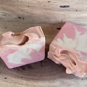 May include: Two bars of handmade soap with a pink and white swirl pattern. The soap is made with natural ingredients and is perfect for sensitive skin.