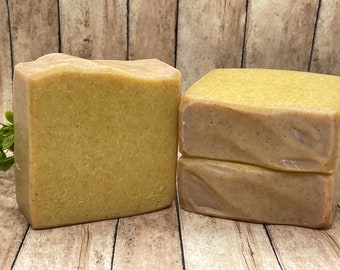 May include: Two bars of handmade soap, one is a single bar and the other is a stack of two bars. The soap is a light brown color with a speckled appearance.