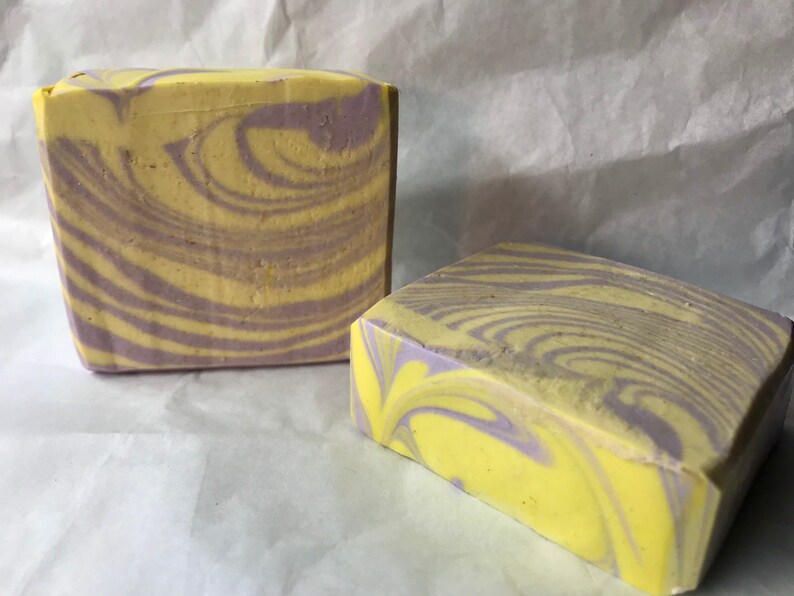 May include: Two bars of handmade soap with a swirl pattern in shades of yellow and purple.
