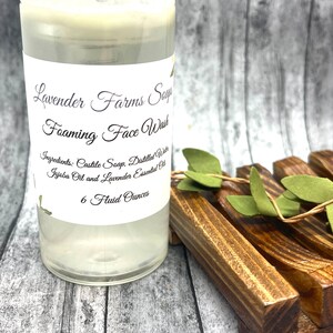 May include: A clear plastic bottle with a white label that reads "Lavender Farms Soap Foaming Face Wash" and lists the ingredients as "Castile Soap, Distilled Water, Jojoba Oil and Lavender Essential Oil". The bottle contains a clear liquid and is labeled "6 Fluid Ounces".