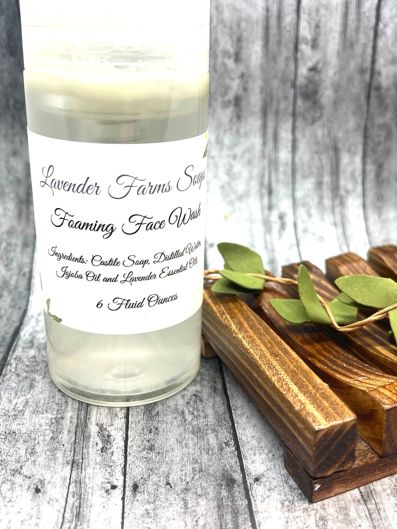 May include: A clear plastic bottle with a white label that reads "Lavender Farms Soap Foaming Face Wash" and lists the ingredients as "Castile Soap, Distilled Water, Jojoba Oil and Lavender Essential Oil". The bottle contains a clear liquid and is labeled "6 Fluid Ounces".