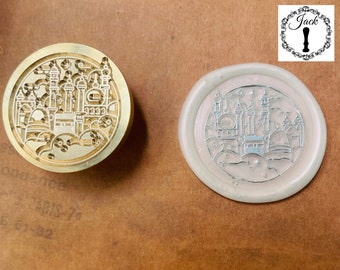 May include: A brass wax seal stamp featuring a detailed design of a city skyline. The stamp is used to create a wax seal with a matching design. The wax seal is white and has a silver sheen.