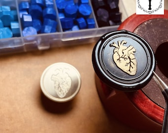 May include: Two wax seals with a gold anatomical heart design. One seal is black and the other is silver.