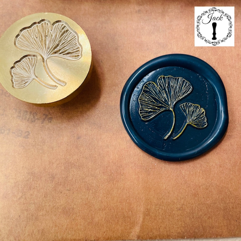 May include: A gold metal stamp with a design of two ginkgo leaves. A blue wax seal with a gold ginkgo leaf design.