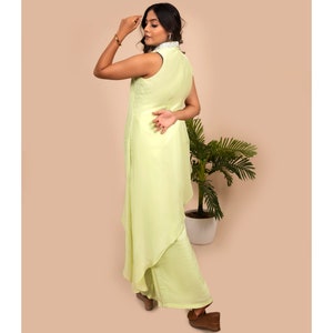 May include: A light green sleeveless dress with a high collar and a layered skirt. The dress is made of a soft, flowing fabric.