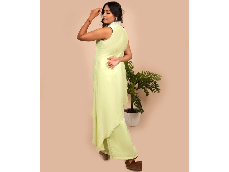May include: A light green sleeveless dress with a high collar and a layered skirt. The dress is made of a soft, flowing fabric.