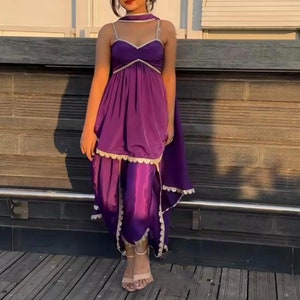 Puede incluir: Un vestido morado con escote de coraz&oacute;n y ribete de encaje. El vestido tiene una falda fluida y se combina con pantalones morados a juego.
