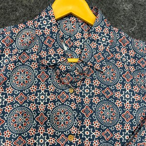 Op de afbeelding: Een blauw-wit gepatroneerd overhemd met rode accenten. Het overhemd heeft een knoopsluiting en een kraag.