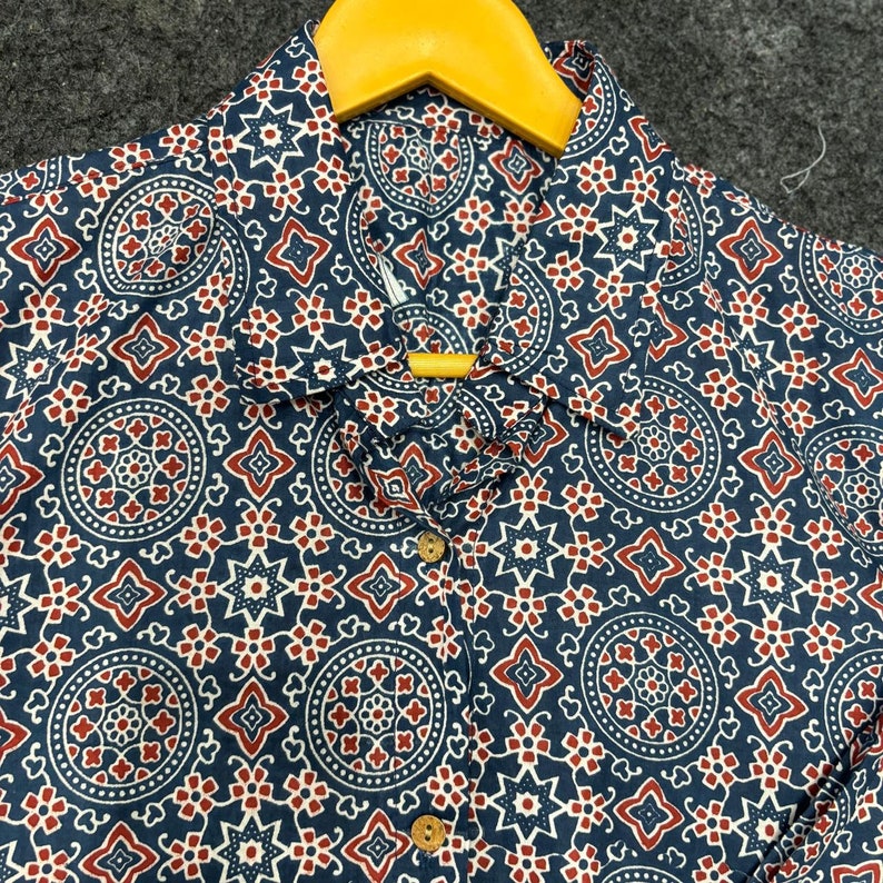 Op de afbeelding: Een blauw-wit gepatroneerd overhemd met rode accenten. Het overhemd heeft een knoopsluiting en een kraag.