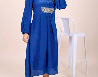 May include: A royal blue midi dress with long sleeves and a high neckline. The dress features a silver and gold embroidered design on the bodice.