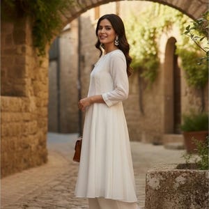 Three-quarter profile, showing flared floor-length silhouette and delicate tie-neck detail, white anarkali suit