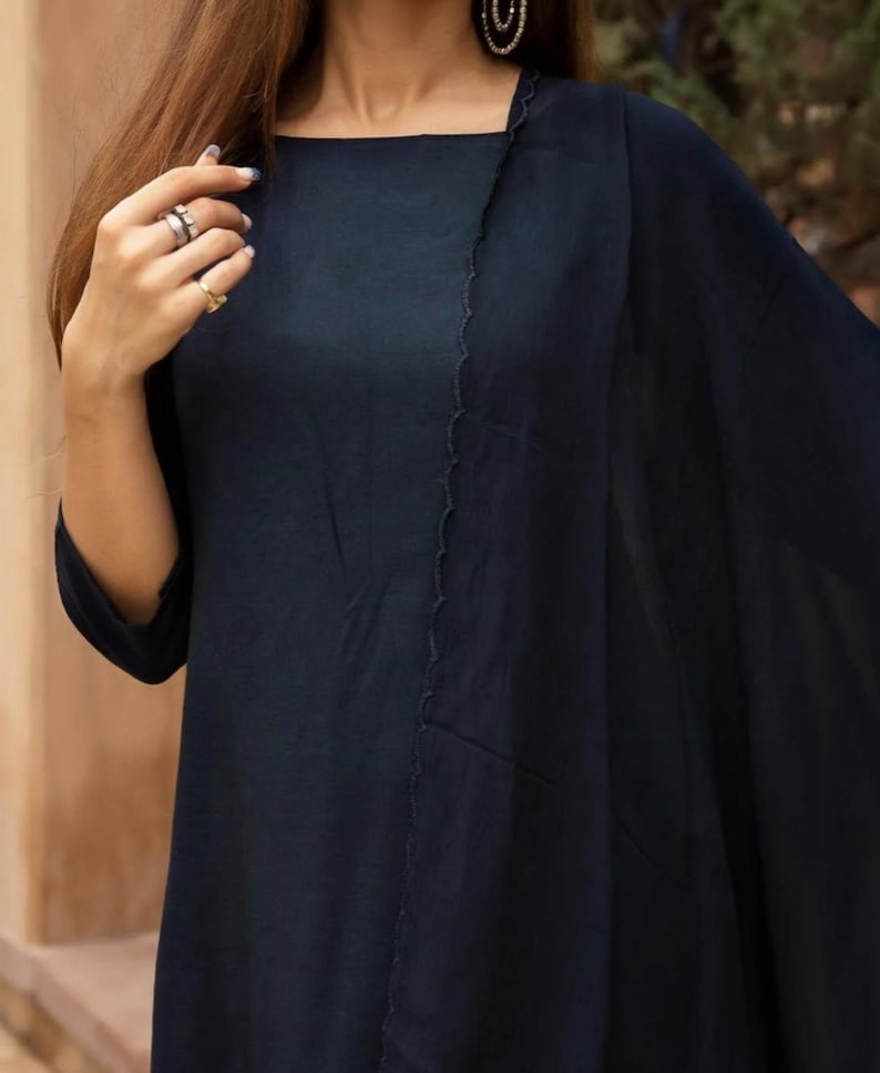 May include: A navy blue long-sleeved tunic with a high neckline and a single, angled seam on the front. The tunic is made of a lightweight fabric and has a flowing silhouette.