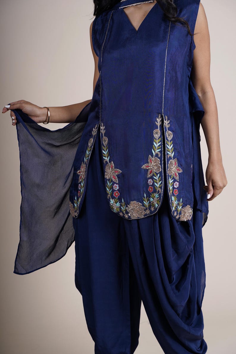 A blue sleeveless top with floral embroidery and a matching blue dhoti pant. The top has a keyhole neckline and a slit on the front. The dhoti pant has a loose fit and is gathered at the waist.