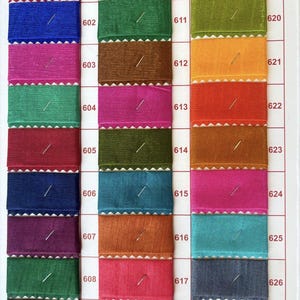 Pu&ograve; includere: Una cartella colori con 10 righe di campioni di tessuto. Ogni riga ha 3 campioni, con i numeri 601-627 etichettati sul lato destro della cartella. I campioni sono di vari colori, tra cui rosso, blu, verde, marrone, arancione, giallo, rosa, turchese, grigio e beige.