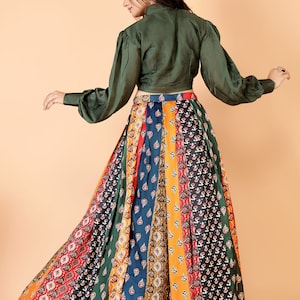 May include: A long, flowing skirt with a patchwork design in various colors, including red, orange, green, and blue. The skirt is paired with a dark green long-sleeved top. The outfit is suitable for a variety of occasions.